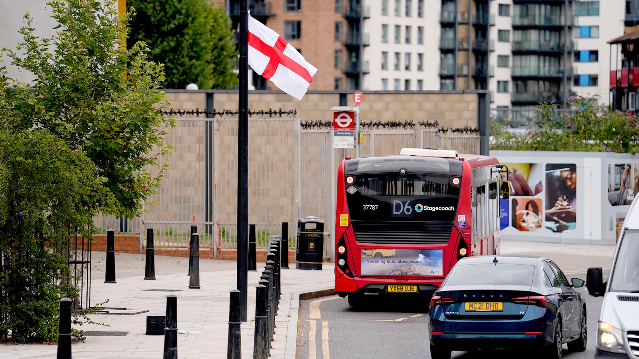 Red bus on a city street with a flag and buildings in the background